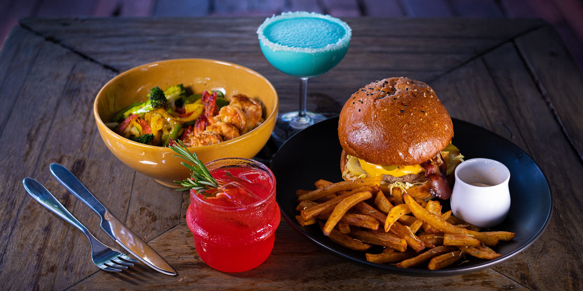 MESTO dinner spread with two cocktails, a shrimp rice bowl, burger and hand-cut fries
