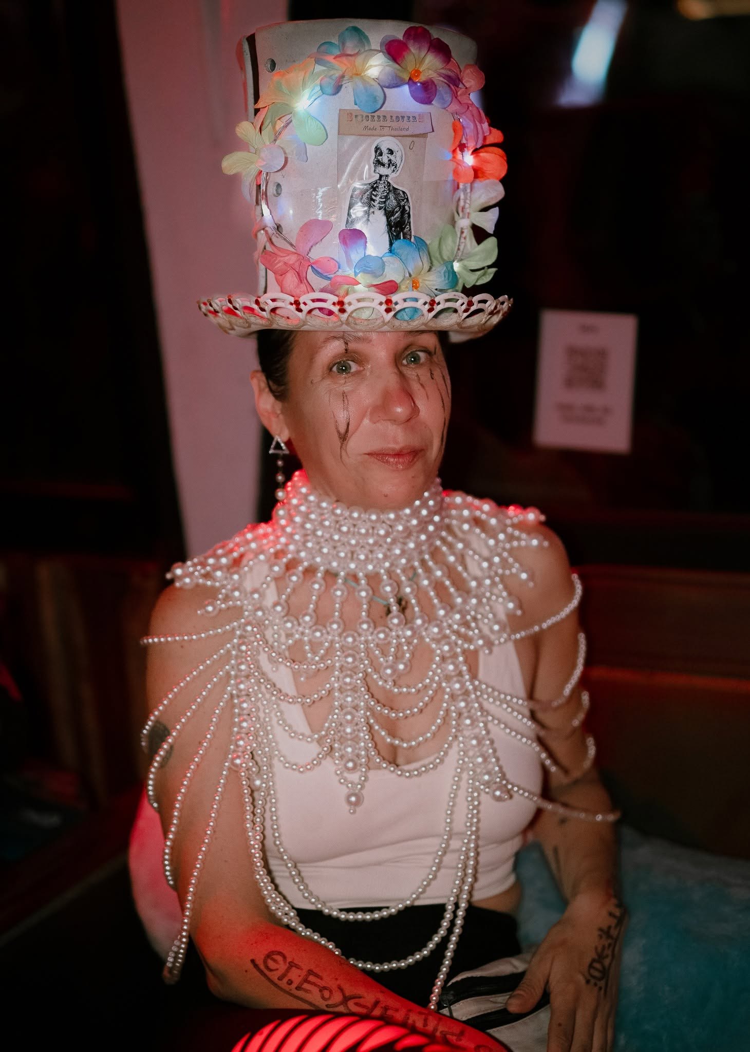 A guest in an inventive flower-covered top hat and pearl accessories