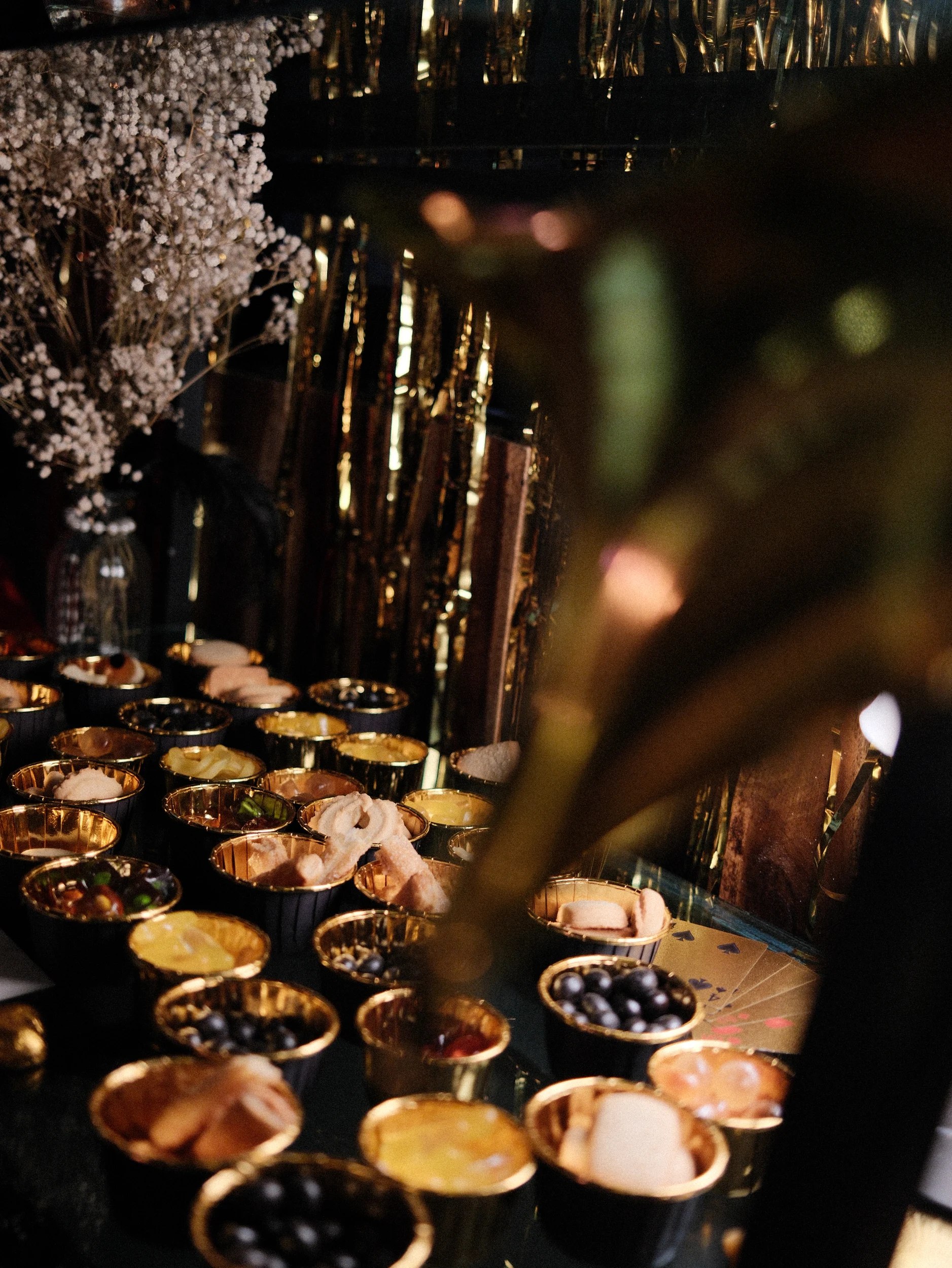 Snacks presented in gold bowls beside playing cards and candlelight