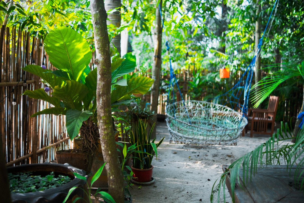 A hand-woven swing surrounded by lush plants in the MESTO tropical garden